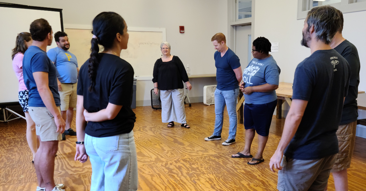 A diverse group of adults stand in a circle learning improv in New Orleans.